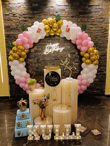 A pink, white, and gold ring-themed birthday decoration. The setup includes a neon sign and marquee letters, creating a beautiful and personalized display.