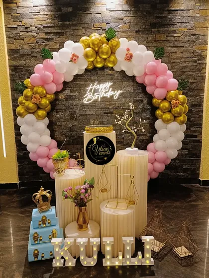A beautiful ring-themed birthday decor in pink, white, and gold. The balloon arch, neon sign, and plinth arrangement create an elegant photo corner.