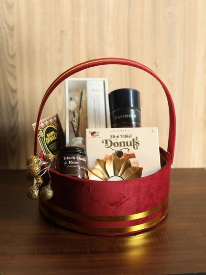 This luxurious red velvet basket is designed to pamper. It contains Davidoff coffee, a black oudh and rose candle, a reed diffuser, donuts, and a decorative diya.