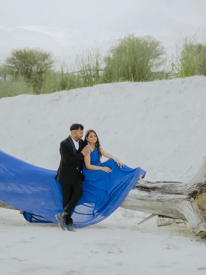 A relaxed and romantic pose on a fallen log. The contrast of the elegant blue gown against the raw, natural elements makes for a compelling photograph.
