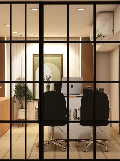 A view into a private office through a modern, black-framed glass partition. This design choice creates a sense of transparency and openness while still defining a separate, quiet workspace.