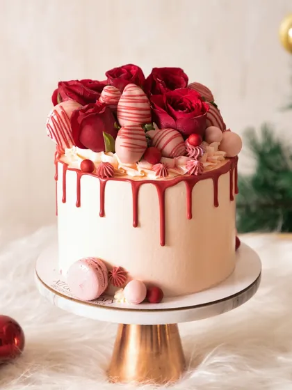 A gorgeous drip cake for the holidays, topped with fresh red roses and chocolate-dipped strawberries. It's festive, romantic, and delicious.