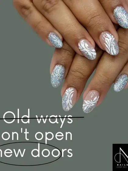 A wintery and elegant design. This set features full-coverage silver glitter nails paired with sheer-based nails that have intricate, hand-painted white patterns.