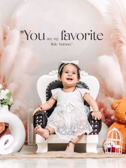 A joyful and expressive portrait from a first birthday studio session. The clean, bright setup with boho elements allows the child's happy personality to shine.