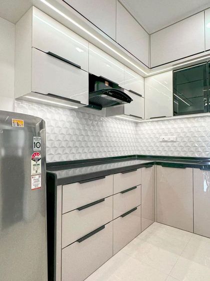 A close-up of the cooking area in this dual-tone kitchen, with the chimney neatly integrated between the handle-less upper cabinets.