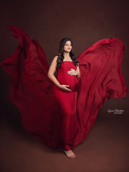 Glowing and growing. This shot captures the beauty of a simple red gown with a long train, enhanced by the dynamic fabric toss.