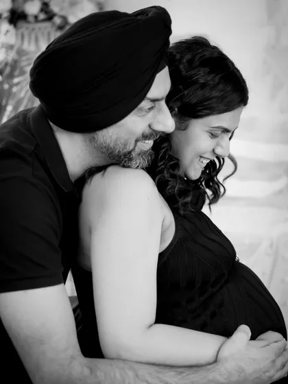 A candid black and white shot full of laughter and joy. This image captures a genuine, happy moment between the expecting couple.