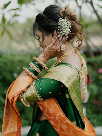 A professional shot of a bride on her wedding day, her mehendi peeking through as she adjusts her hair.