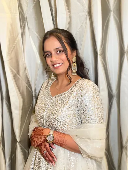 A smiling portrait of the client, her hair pulled back to show off her beautiful makeup and earrings.