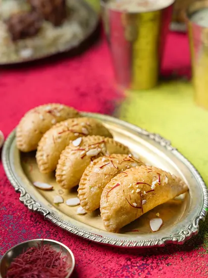 A festive shot for a biryani brand's Holi campaign. The colorful background and traditional silver platter make the gujiyas look celebratory and delicious, perfectly aligning with the festival's spirit.