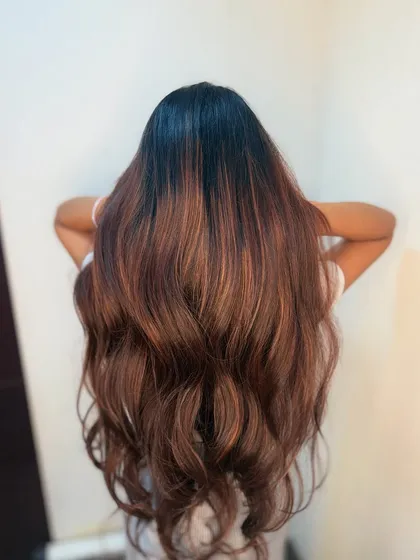 A beautiful shot of the client holding up her long, wavy, balayage hair. The color looks rich and vibrant.