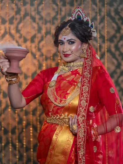 This image captures a traditional Bengali wedding ritual. The makeup is designed to be sweat-proof and long-lasting, staying perfect throughout the ceremonies.