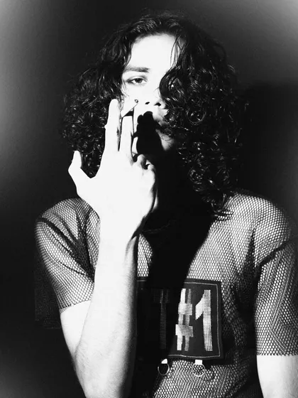 A grainy, high-contrast black and white shot with a rebellious feel. The composition is tight and the model's gesture is confrontational, creating a raw and energetic portrait.