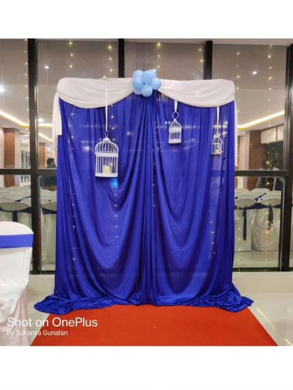 A simple yet elegant photo booth backdrop perfect for any special occasion. The rich royal blue curtain, accented with white draping, fairy lights, and decorative birdcages, creates a classic look.