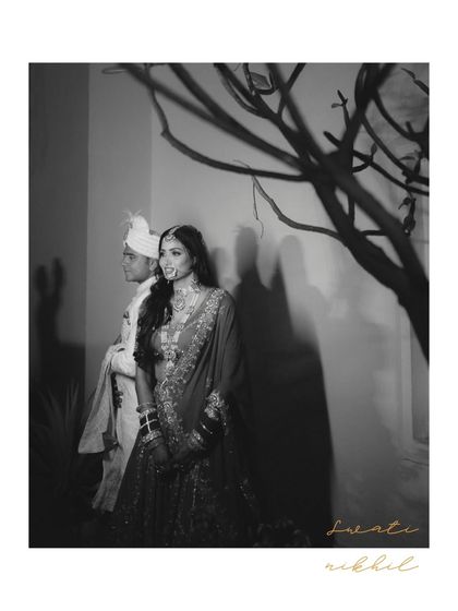A moody black and white portrait of the couple, framed by the shadow of a tree. It's an artistic and timeless shot from their wedding day.