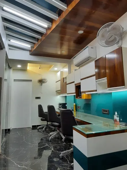 This image shows a functional staff workspace with a long counter, teal back-painted glass, and a combination of open and closed overhead storage. The wooden ceiling detail adds warmth to the sleek, modern design.