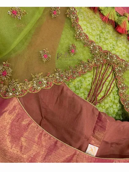 A close-up of the pink and green blouse, showing the intricate details of the embroidery and the playful tassels.