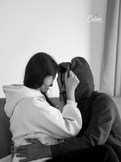 An artistic and intimate black and white shot where the couple connects under a hoodie.