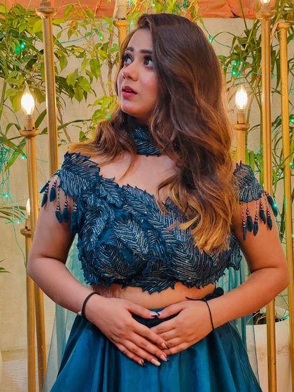 A close-up on the feather-like embroidery of the teal blouse. The details on this piece are what make it a true showstopper.