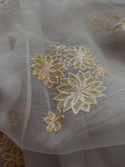 This embroidered organza features beautiful golden floral embroidery on a sheer base, creating a look of dreamy, detailed elegance perfect for special occasions.