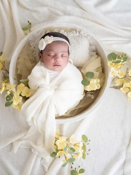 A wider, top-down shot shows the full styling of this sunny and cheerful floral setup, with the baby perfectly swaddled and secure.