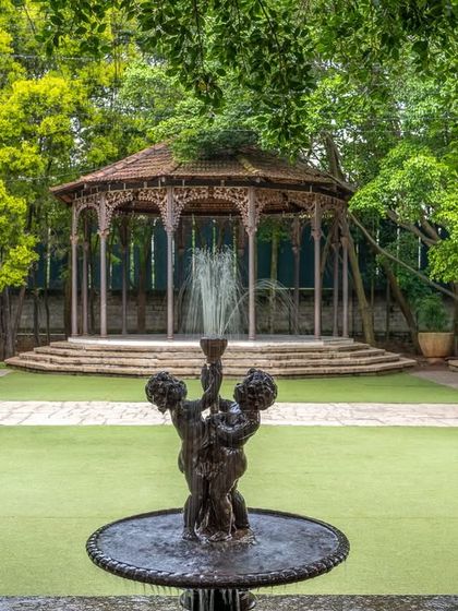 The colonial bandstand, with its intricate pillars from pre-independence Calcutta, stands as a centerpiece on our main lawn, watched over by a classic fountain.