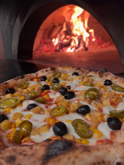 Our Classic Veg pizza, hot from the wood-fired oven. Topped with corn, olives, and jalapeños.