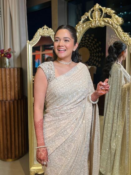 A candid, happy moment in a glamorous, sparkling white saree. The makeup is chic and modern, with a sleek ponytail and a luminous glow, perfect for a reception or Sangeet night.
