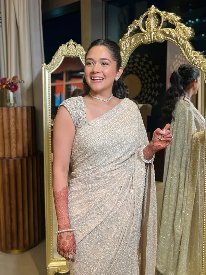 A candid, happy moment in a glamorous, sparkling white saree. The makeup is chic and modern, with a sleek ponytail and a luminous glow, perfect for a reception or Sangeet night.