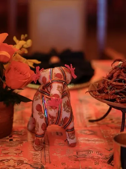 A playful and unique decor detail, featuring a small, fabric-covered elephant figurine next to a bowl of dried red chilies.