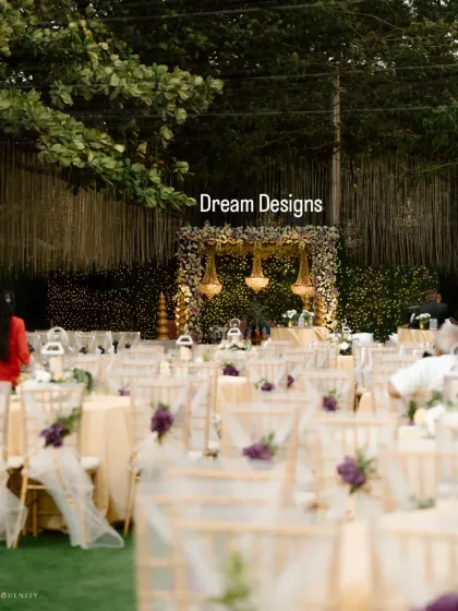 A view of the ceremony space from the guest's perspective. The chairs are elegantly decorated, leading the eye towards the mandap which is lit by stunning crystal chandeliers.