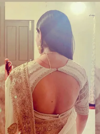 This elegant white blouse features a circular open-back design with delicate silver embroidery along the edges. It's a modern and chic option for receptions or pre-wedding events.