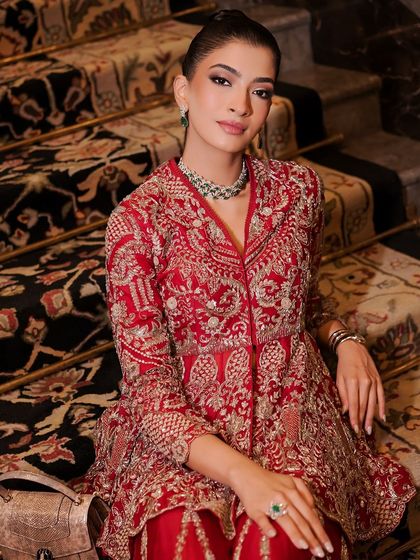 The full look, with the model seated on a grand staircase. The makeup is elegant and refined, a perfect match for the luxurious setting and couture outfit.
