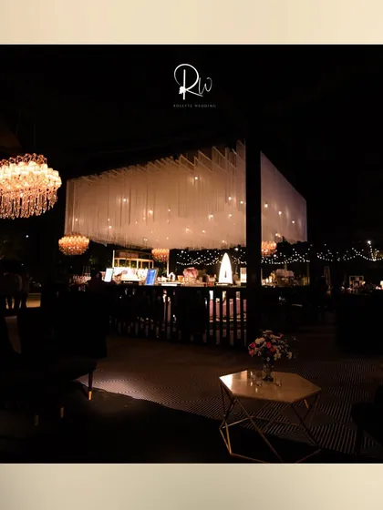 A wide view of a cocktail event, showing the bar area with a unique white fabric ceiling installation and multiple chandeliers.