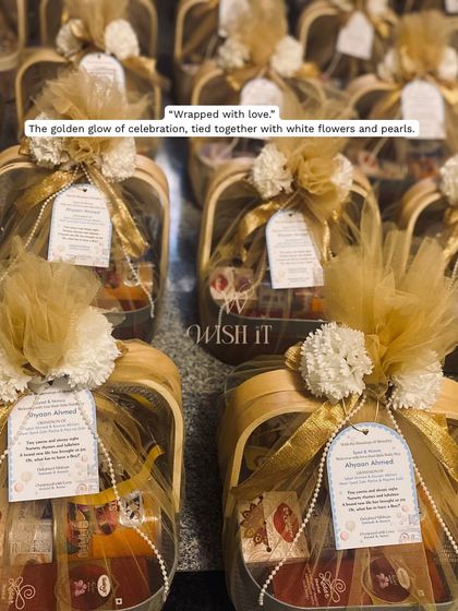 The final look of the naming ceremony return favors. The golden glow of the wrapping, tied with white flowers and pearls, gives each basket a celebratory feel.