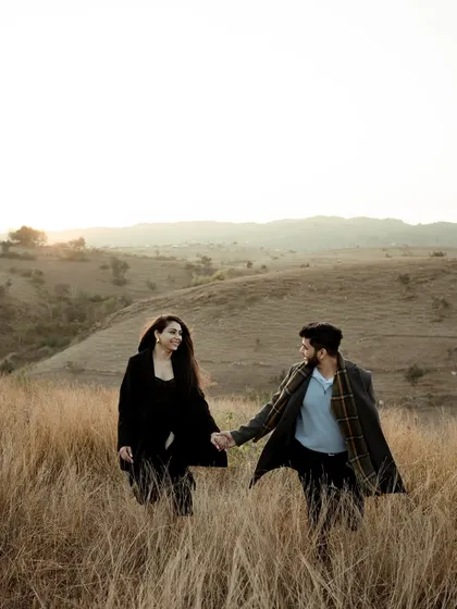 A classic "follow me" shot in a field of tall grass at sunset. The warm light and the couple's connection make this a timeless and romantic pre-wedding photograph.
