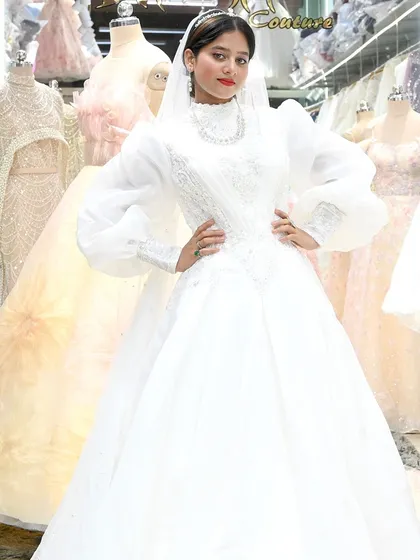 A powerful pose from a bride in her high-neck, bishop-sleeved gown. The clean lines and sophisticated silhouette make a bold statement.