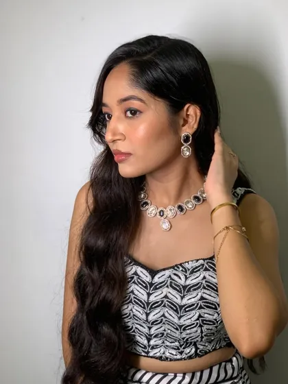 A perfect blend of elegance and sophistication. This monochrome look for a cocktail event is enhanced with a subtle smokey eye, a flawless base, and soft, open waves for a captivating finish.