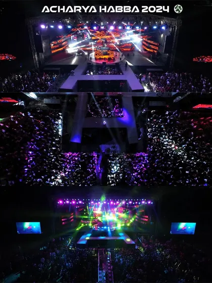 An aerial top-down shot capturing the immense crowd and spectacular stage lighting at Acharya Habba 2024. This perspective, only possible with professional drone videography, shows the sheer scale of the event and the energy of the audience.