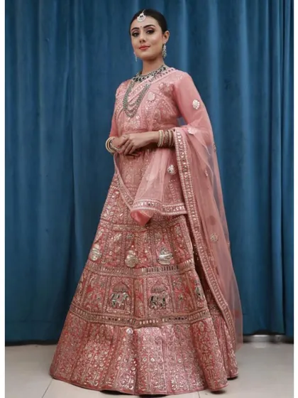 The full view of this traditional peach-pink lehenga highlights its intricate craftsmanship and timeless appeal. A perfect rental for a classic, elegant look.