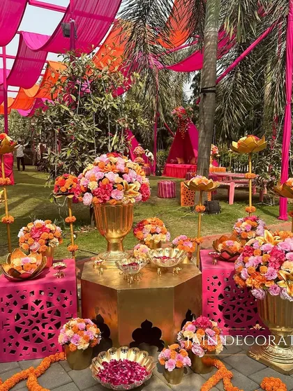 A corner dedicated to floral abundance. Bright pink and orange flowers overflow from golden vases, creating a rich and festive display that adds to the celebratory mood.