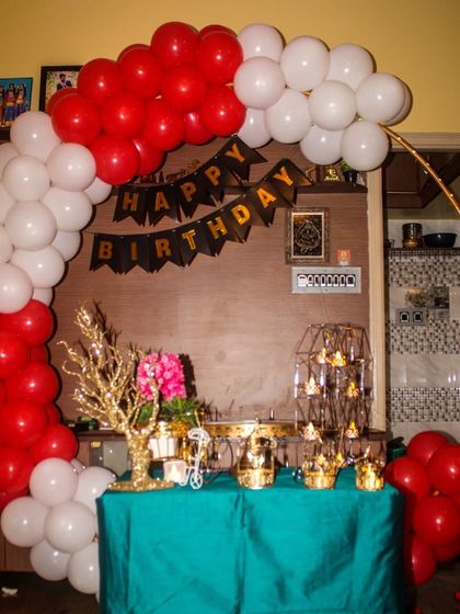 A simple yet classic birthday decoration for an at-home party. We used a red and white balloon arch on a gold ring frame, setting up a small table for the cake and gifts, making it easy to celebrate in any room.