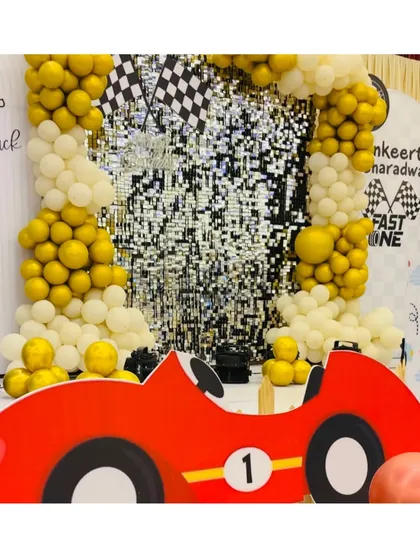 Full throttle for a first birthday with this "Fast One" racetrack theme. A shimmering sequin backdrop, balloon arches in gold and white, and a fun car cutout create an exciting and playful atmosphere for a little speedster's big day.
