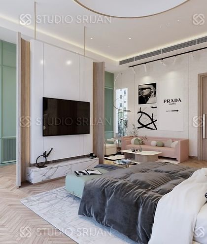 In this spacious Alameda bedroom, I used a floating TV wall as a clever divider to create a distinct dressing area behind it. The room features a soft, pastel color palette with mint green and pink, herringbone wood flooring, and a cozy sitting area.