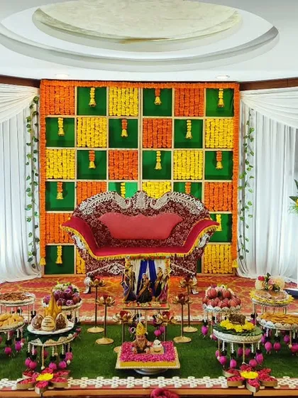 A baby shower setup with a checkered backdrop of green, yellow, and orange flowers. The traditional sofa and plate arrangement create a classic and colorful look.