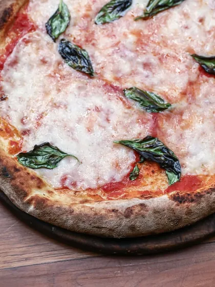 A beautiful Margherita pizza made with our whole wheat sourdough base. It's topped with our special lactose-free cheese, showing our commitment to catering to different dietary needs.
