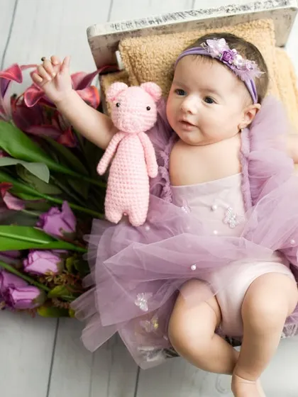 Reaching for the stars. This awake baby is stretching out, full of life and energy, surrounded by beautiful purple flowers.