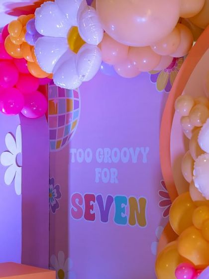 Another view of the "Too Groovy for Seven" backdrop, highlighting the layered arches and intricate balloon work that create depth and visual interest.