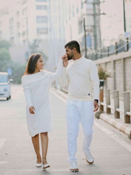 A full-length shot of a couple walking down a city street, with the groom gently kissing the bride's hand.