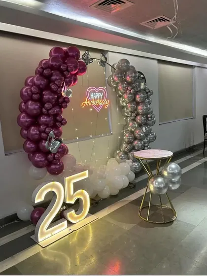 This shot captures the full 25th-anniversary setup, including the light-up numbers, balloon arch, and a small table for the cake.